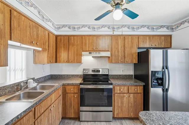 a kitchen with granite countertop a sink stainless steel appliances and cabinets