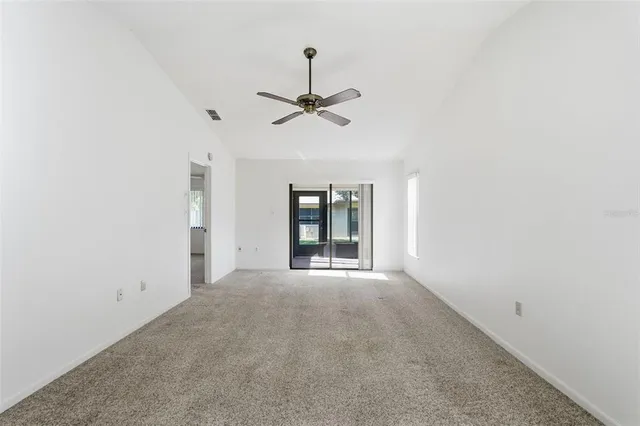 an empty room with windows and ceiling fan