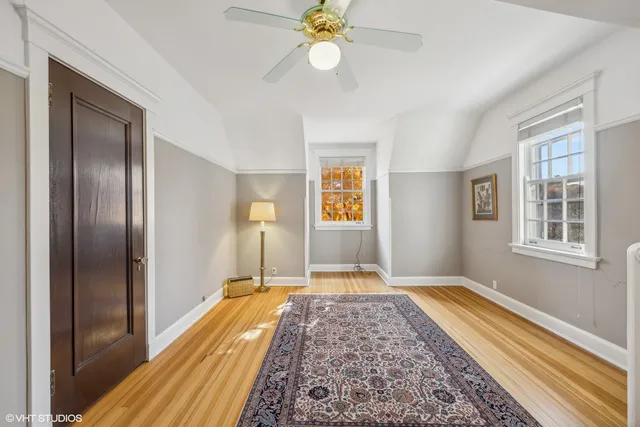 a view of a bedroom with wooden floor and a chandelier fan
