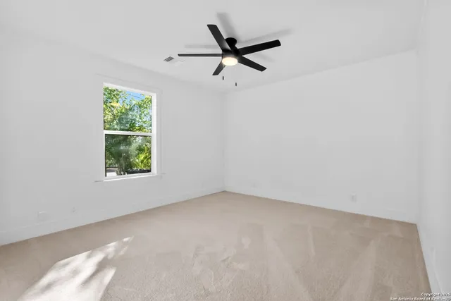 an empty room with windows and fan
