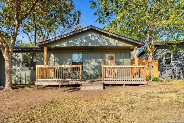 a view of a house with wooden fence and a trees