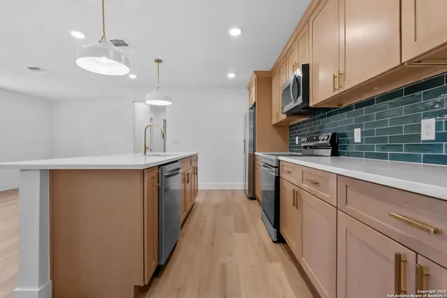 a kitchen with stainless steel appliances granite countertop a sink a stove and a wooden floors