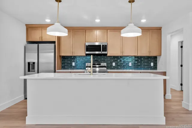 a kitchen with stainless steel appliances granite countertop a sink a microwave a refrigerator and a counter top space