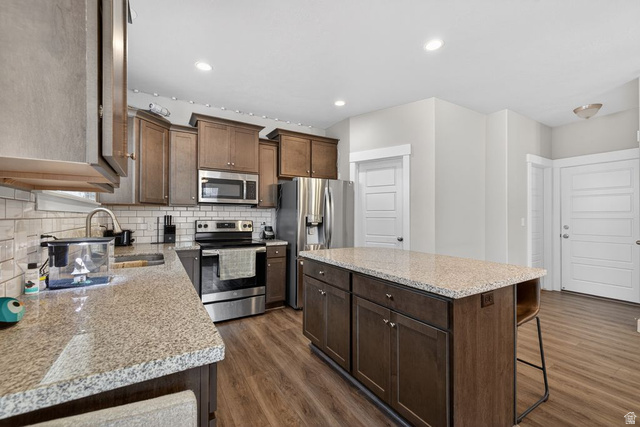 412 McClellan Court Provo, UT 84601 - Photo 3 of 20 Kitchen with a center island, stainless steel appliances, light stone counters, dark wood-type flooring, and a breakfast bar