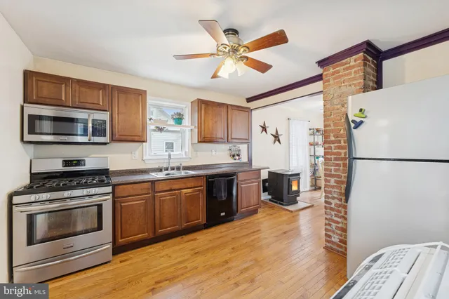 a kitchen with stainless steel appliances granite countertop a stove top oven a refrigerator a sink and white cabinets