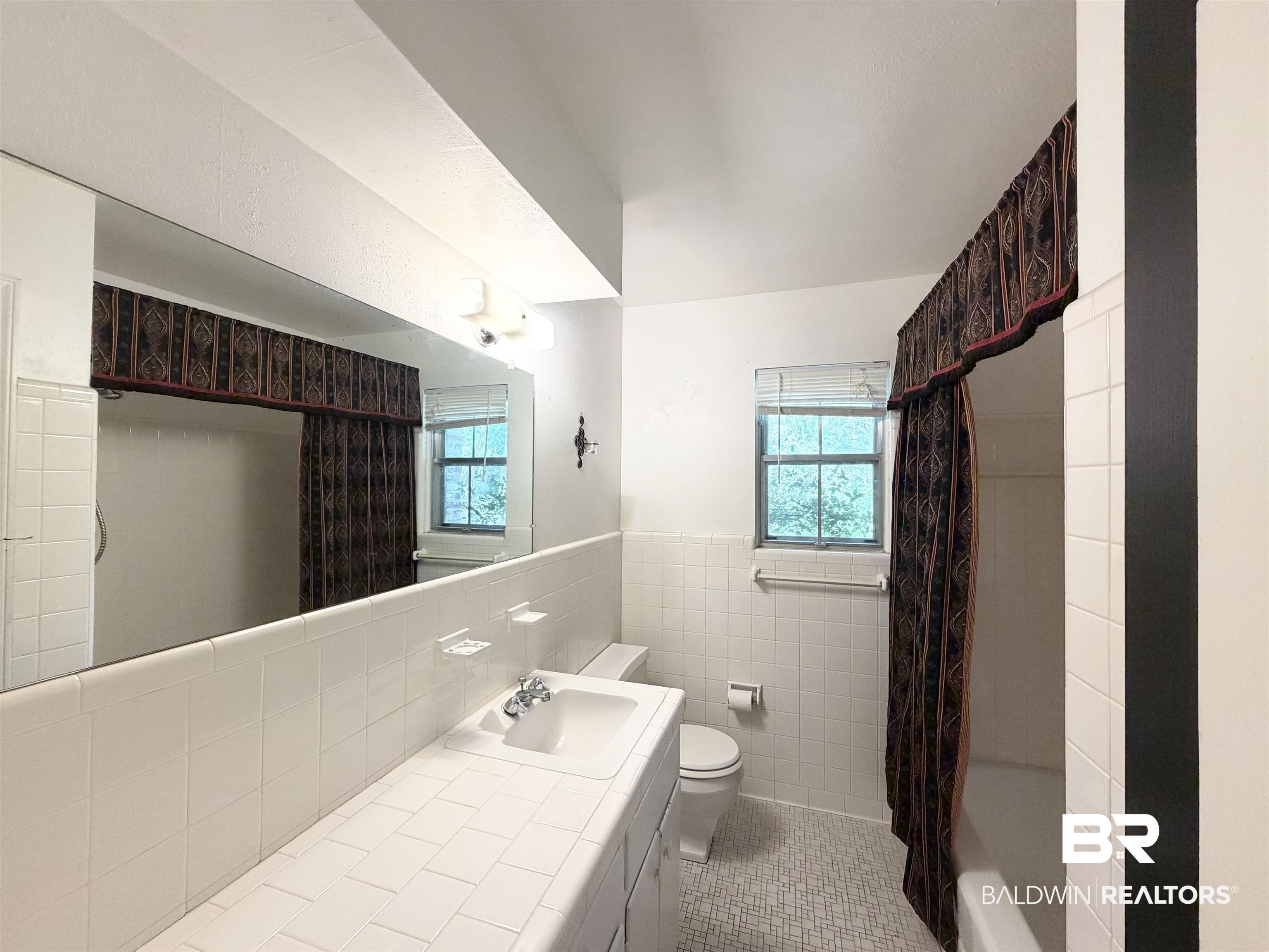 1075 Zurich Street Mobile, AL 36608 - Photo 28 of 35 Full bathroom featuring tile walls, vanity, light tile patterned floors, wainscoting, and shower / bath combination with curtain