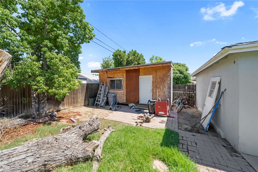 5433 Rochester Street Riverside, CA 92504 - Photo 25 of 29 Rear yard area with a wood-sided outbuilding, mature tree, and brick-paver walkway.