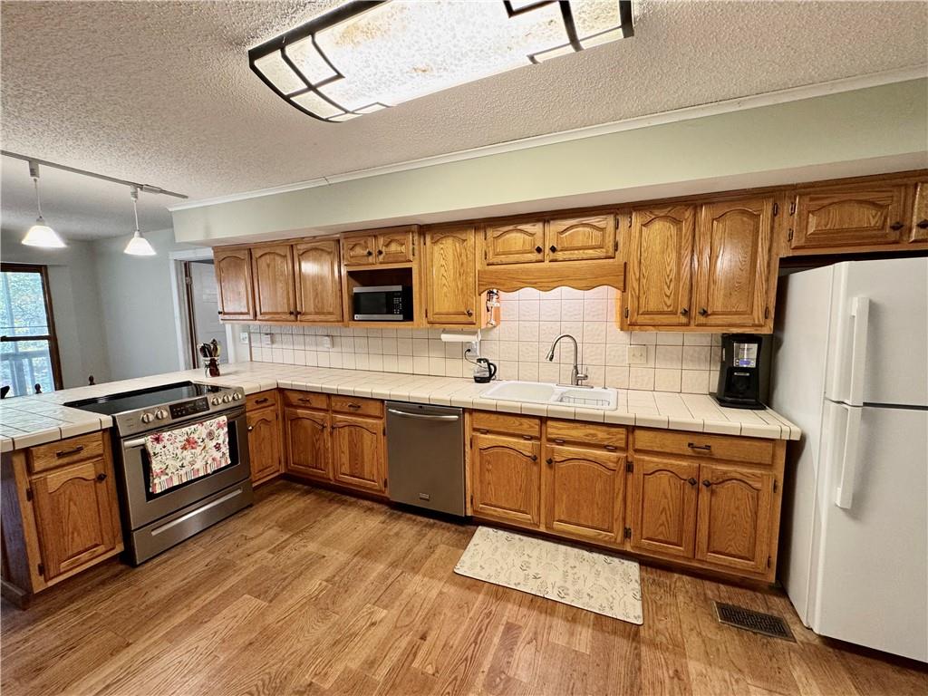 1012 King Mill Road McDonough, GA 30252 - Photo 11 of 64 a large kitchen with stainless steel appliances granite countertop a stove a sink dishwasher and a refrigerator with wooden floor