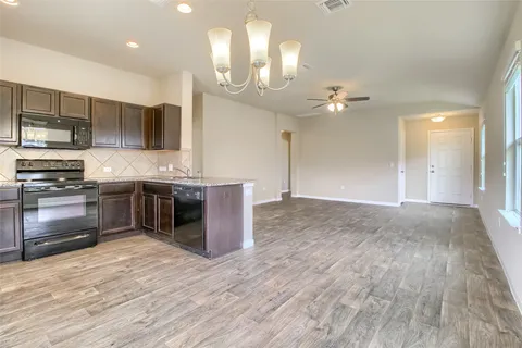 a view of an empty room and a chandelier fan