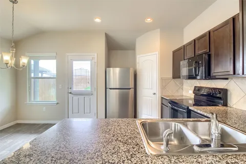 a kitchen with kitchen island wooden floors appliances and cabinets