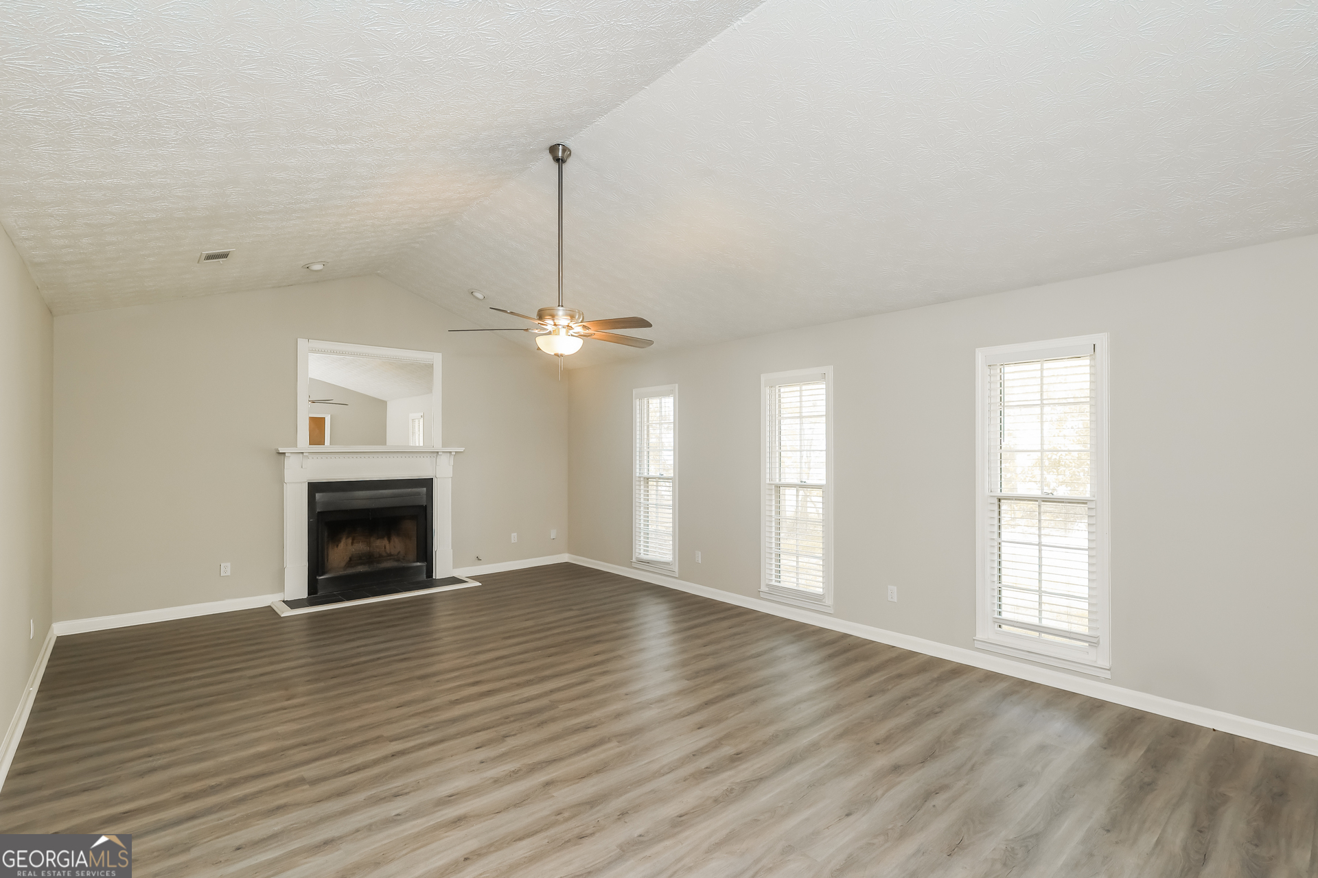 9183 Snipe Lane Jonesboro, GA 30236 - Photo 4 of 22 an empty room with wooden floor fireplace and windows