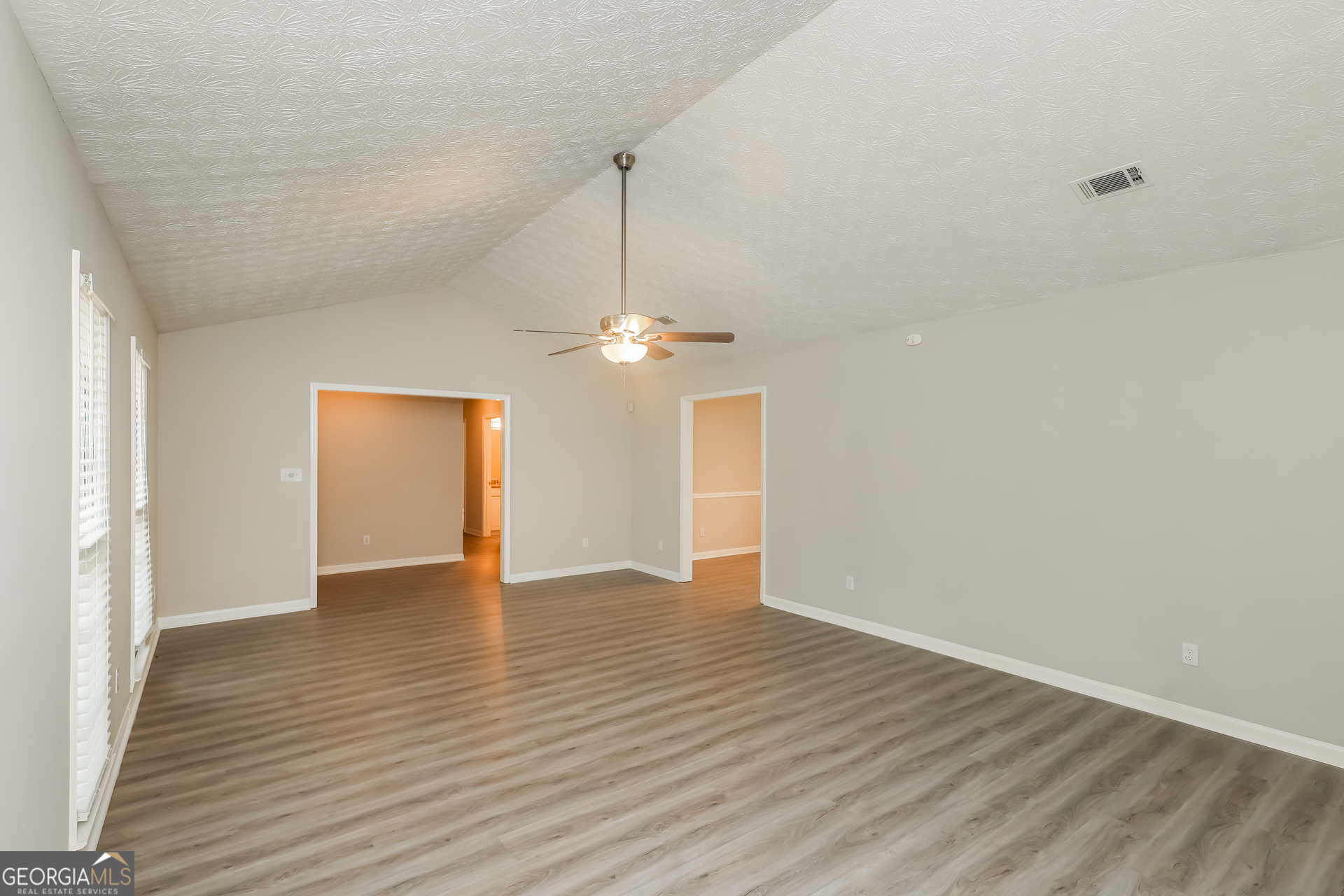 9183 Snipe Lane Jonesboro, GA 30236 - Photo 5 of 22 an empty room with wooden floor chandelier fan and windows
