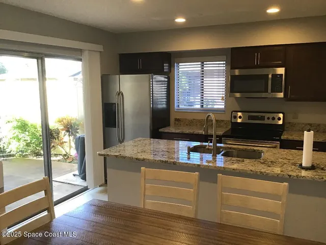 a kitchen with kitchen island granite countertop a stove a sink and a refrigerator