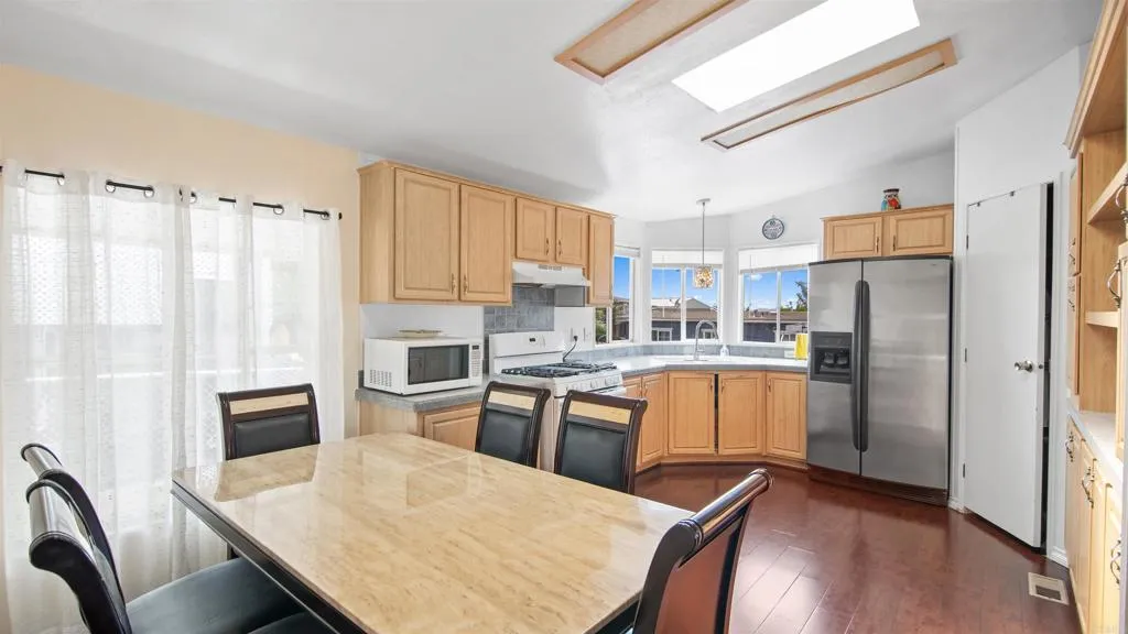 1455 Alturas Street, Unit 55 Fallbrook, CA 92028 - Photo 4 of 31 a kitchen with a refrigerator a stove a sink dishwasher with a dining table and chairs