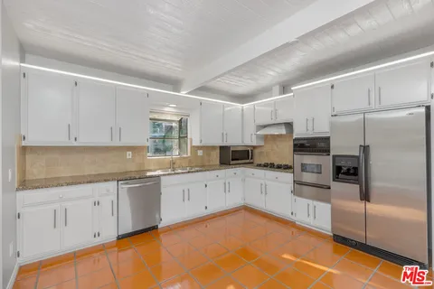 a kitchen with granite countertop a sink stainless steel appliances and cabinets