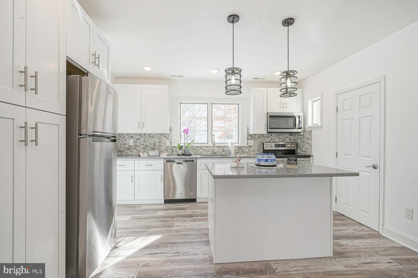 155 Cedar Avenue Pitman, NJ 08071 - Photo 13 of 41 a kitchen with stainless steel appliances kitchen island granite countertop a refrigerator a sink dishwasher a oven with white cabinets and wooden floor
