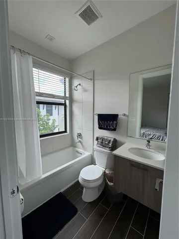 a bathroom with a double vanity sink toilet mirror and window