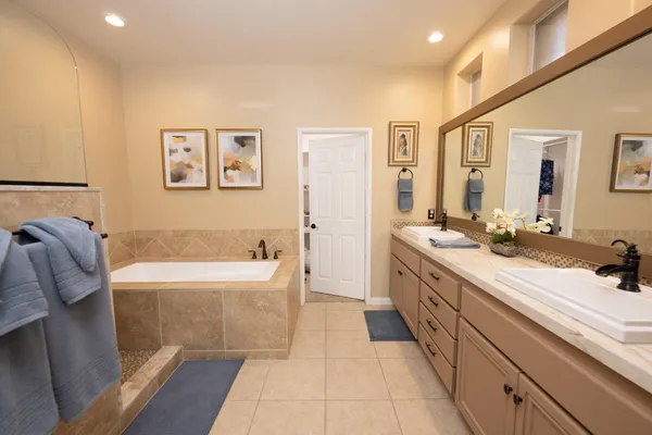 a spacious bathroom with a tub sink and mirror