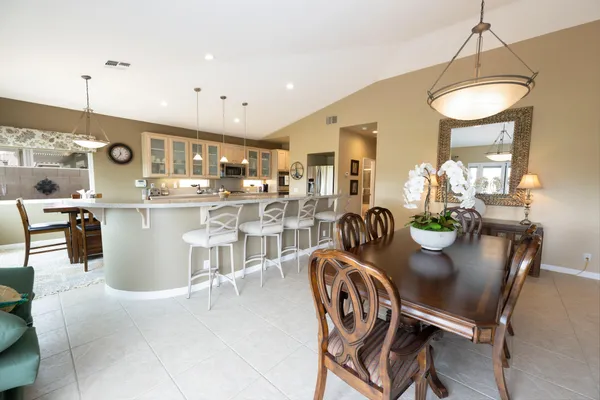 a dining room with stainless steel appliances kitchen island granite countertop a table chairs and a refrigerator