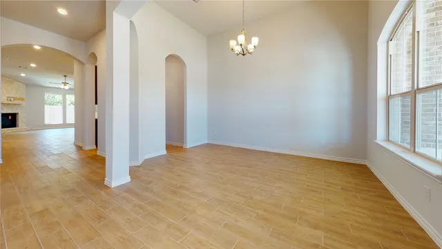 an empty room with chandelier fan and windows