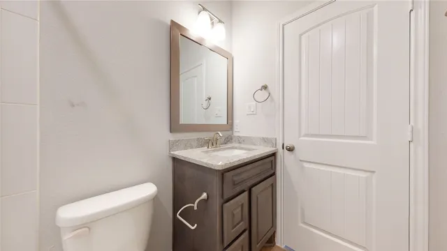 a bathroom with a granite countertop sink and a toilet