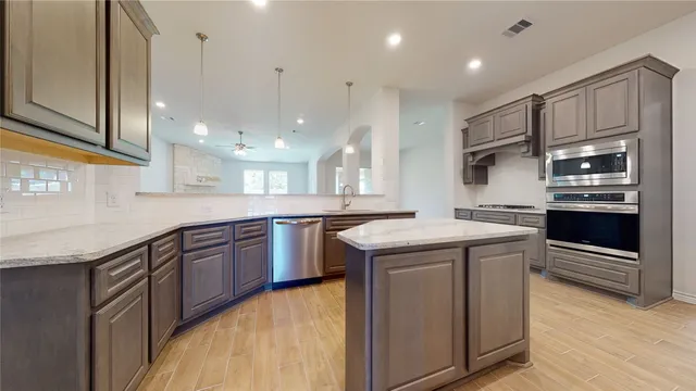 a kitchen with kitchen island granite countertop a sink and stainless steel appliances