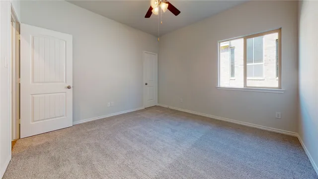 an empty room with chandelier fan and windows