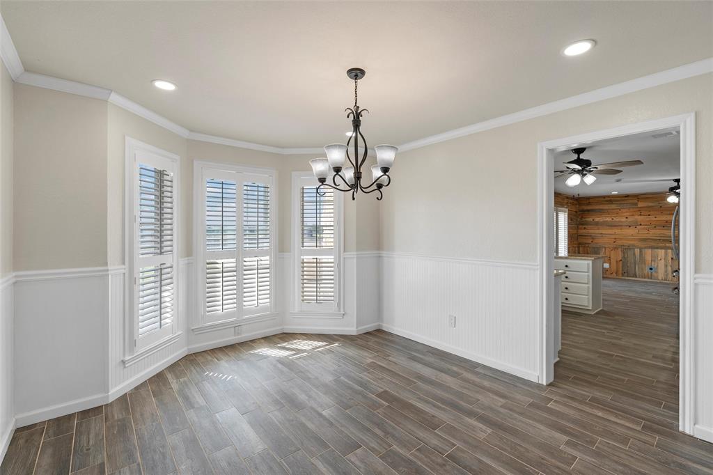 5112 Old Caufield Ranch Road McGregor, TX 76657 - Photo 20 of 38 Unfurnished dining area featuring dark wood finished floors, recessed lighting, a chandelier, ornamental molding, and a wainscoted wall