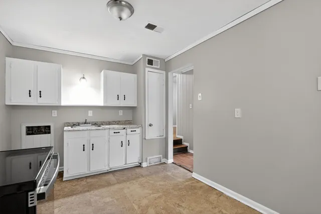 a kitchen with granite countertop a sink a stove and cabinets