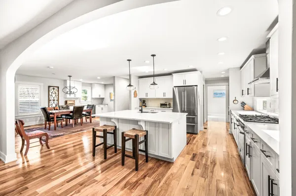 a large kitchen with stainless steel appliances kitchen island granite countertop a sink and dishwasher a stove with the wooden floor