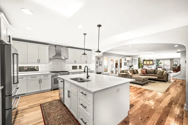 a kitchen with stainless steel appliances granite countertop a stove a sink and a refrigerator with wooden floors