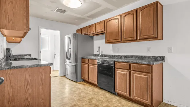 a kitchen with stainless steel appliances granite countertop a refrigerator and a stove top oven