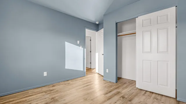 an empty room with wooden floor and closet area