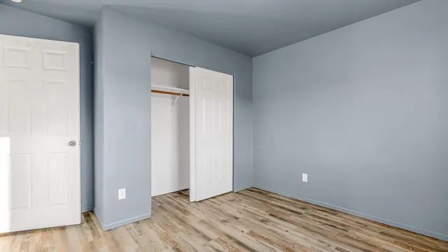 a view of an empty room with closet and wooden floor