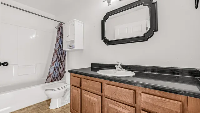 a bathroom with a granite countertop sink a toilet and a bathtub