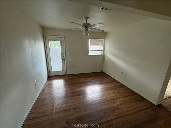 an empty room with wooden floor closet and windows