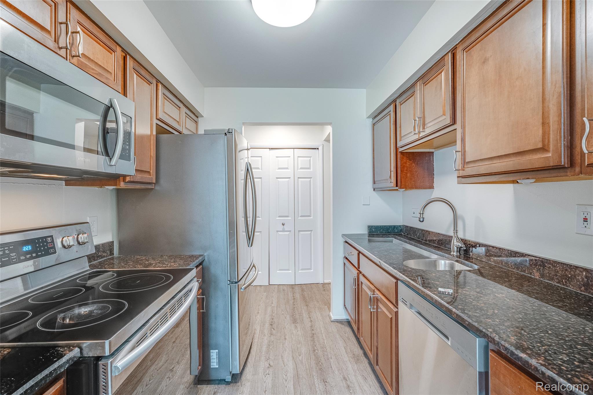29860 West 12 Mile Road, Unit 604 Farmington, MI 48334 - Photo 4 of 26 Kitchen featuring stainless steel appliances, dark stone counters, light wood finished floors, and wood finish cabinetry