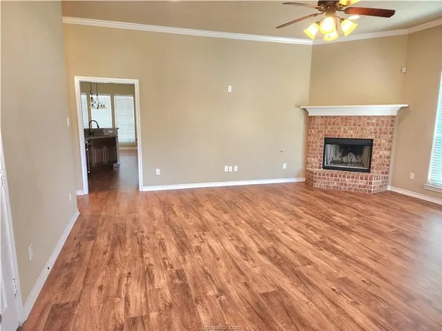 a view of an empty room with wooden floor and a fireplace