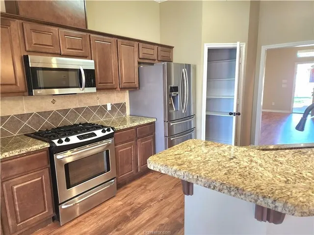 a kitchen with stainless steel appliances granite countertop a stove microwave and refrigerator