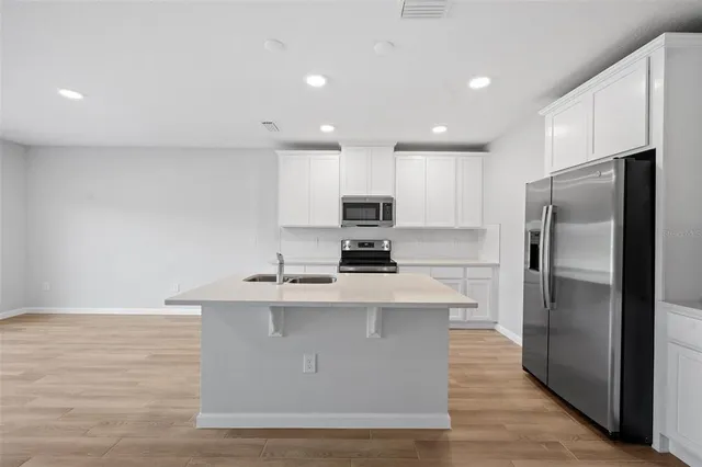 a kitchen with stainless steel appliances granite countertop a stove a refrigerator a sink and a microwave