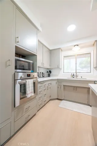 a large white kitchen with granite countertop a large window and white cabinets