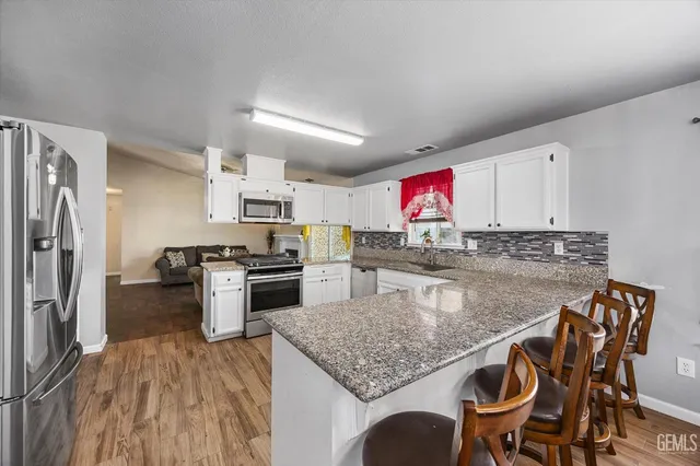 a kitchen with stainless steel appliances granite countertop a kitchen island hardwood floor and a sink