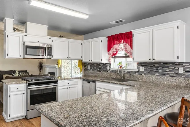 a kitchen with stainless steel appliances granite countertop a stove top oven a sink dishwasher and microwave oven with cabinets