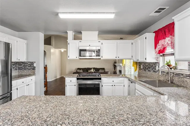 a kitchen with granite countertop a stove top oven sink and cabinets