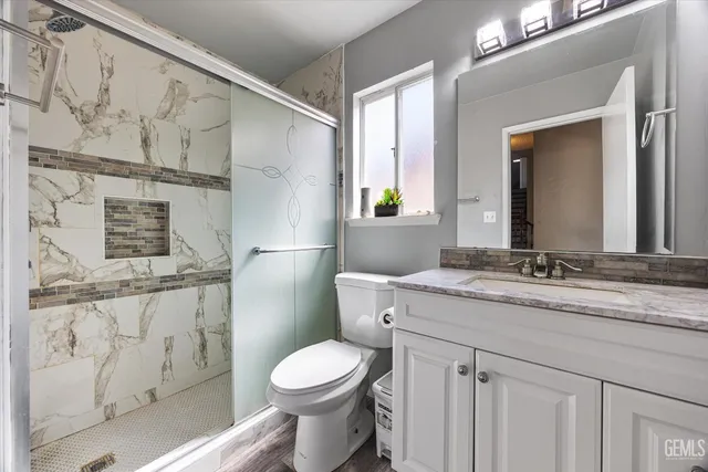 a bathroom with a granite countertop toilet sink and mirror