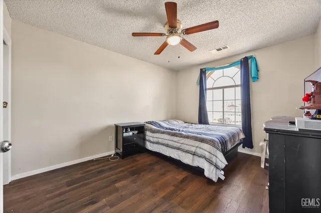a spacious bedroom with a bed and a dresser with wooden floor