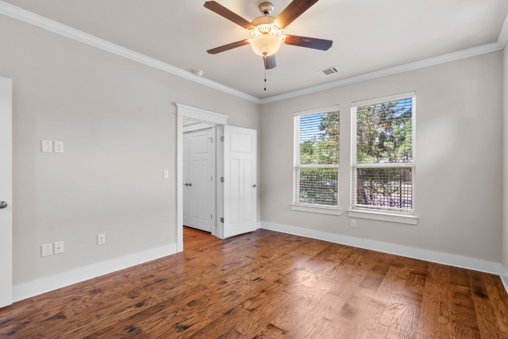 11229 Avery Station Loop, Unit 36 Austin, TX 78717 - Photo 13 of 37 Empty room featuring crown molding, dark wood finished floors, and ceiling fan