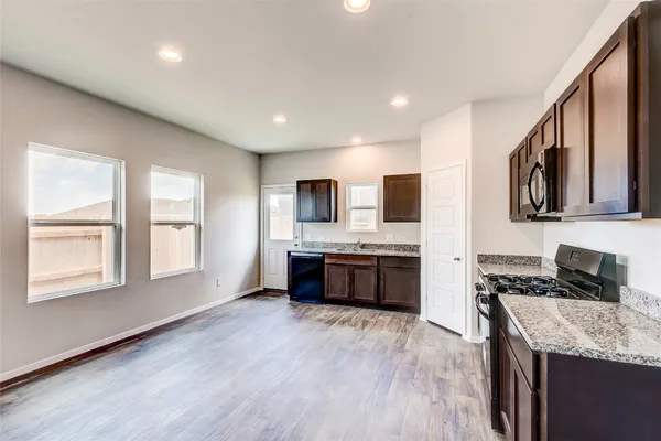 a large kitchen with stainless steel appliances granite countertop a stove a sink dishwasher and a microwave oven with wooden floor