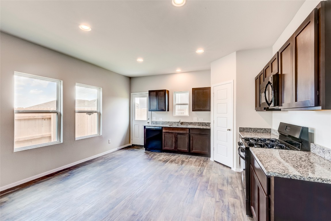 a large kitchen with stainless steel appliances granite countertop a stove a sink dishwasher and a microwave oven with wooden floor