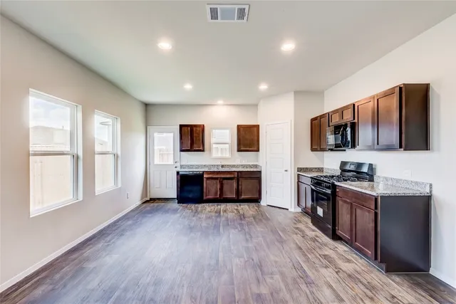 a large kitchen with stainless steel appliances wooden floors and wooden cabinets